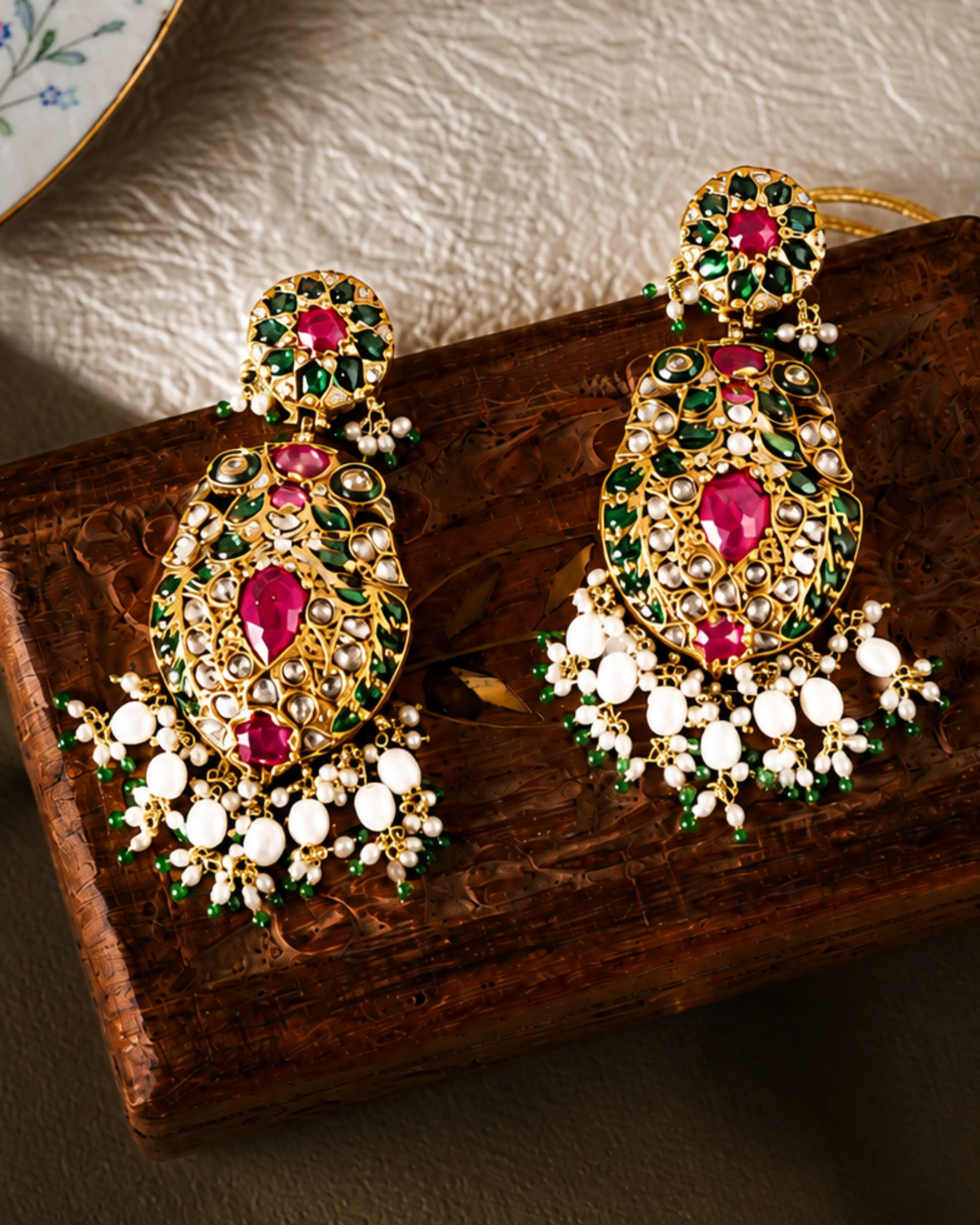 Jadau earrings with a ruby centre, carved emerald leaves and pearl clusters